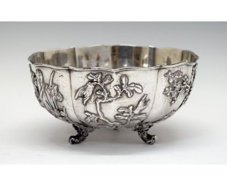 Chinese silver circular bowl decorated with birds and foliage in relief and standing on triple scroll feet, maker Hung Chong,