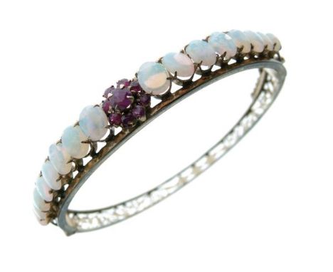 Opal and ruby hinged bangle, unmarked, the frontispiece with a graduated row of sixteen opals and a central cluster of nine r