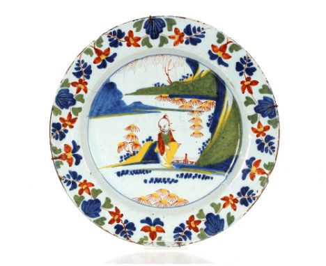 An 18th Century London Delftware charger,&nbsp;painted in iron red, yellow, green and blue, decorated with a Chinese boy in a