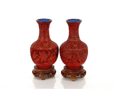 A pair of Chinese cinnabar lacquered vases, on wooden stands of baluster form with blue enamel interiors decorated floral res