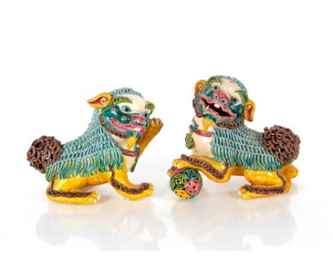 A pair of Chinese pottery Foo lions,&nbsp;each with mischievous expressions applied with pipe work to replicate fur, each wit