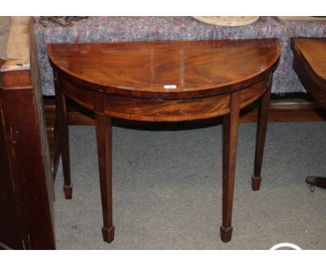 A George III mahogany and rosewood cross banded demi-lune card table,&nbsp;raised on square tapering supports and spade feet,