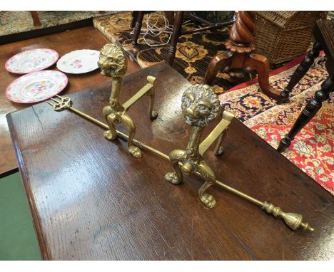 A pair of 19th Century cast brass lion fire dogs with brass toasting fork
