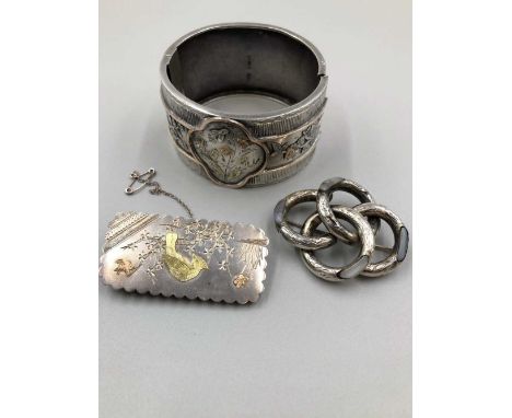A Victorian antique silver cuff bangle with floral gold decoration, a similar silver brooch with a bird design, and a further