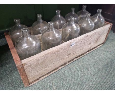 A wooden crate containing ten vintage glass spirit bottles