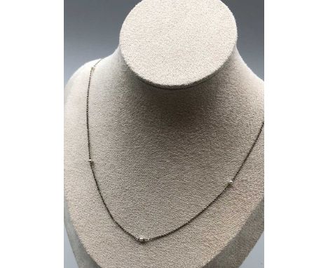 A vintage platinum and pearl "tin-cup" station necklace. No hallmarks visible, assessed as platinum. Length 51cms. Weight 2.2