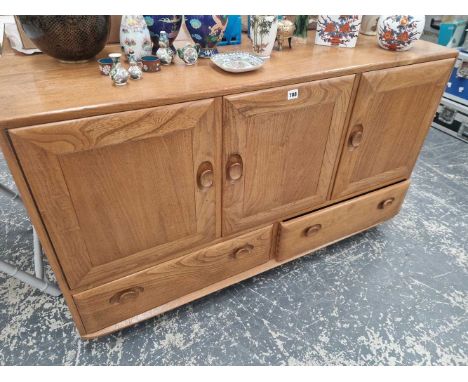 An Ercol elm small sideboard with three doors over drawers 129 x 43 x 77 cm high