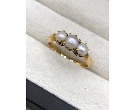 A vintage three-stone pearl ring. The shank with partial hallmarks, is assessed as 18ct gold. Finger size N. Weight 3.29grms.