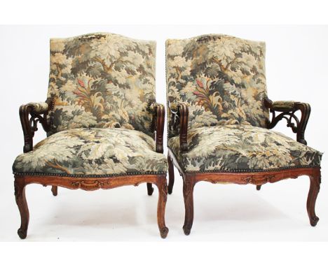 A PAIR OF FRENCH OAK FRAMED AND TAPESTRY UPHOLSTERED ARMCHAIRS with shaped backs, carved and scrolling open arms over overstu