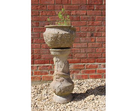 A WEATHERED RECONSTITUTED STONE GARDEN PLANTER on plinth base cast with dragons, 85cm high