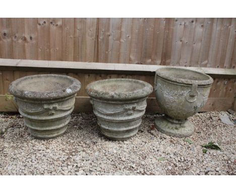 A RECONSTITUTED STONE PLANTER OR URN with grape decoration and moulded ring handles on a circular spreading base, 47cm diamet