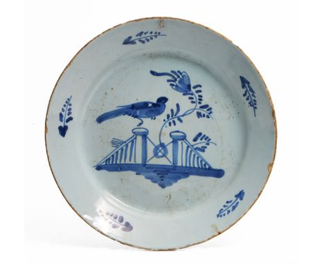 A GEORGE III BRISTOL DELFTWARE PLATE decorated with a bird perched on a fence, 21.8cm diameter (hairline crack) 