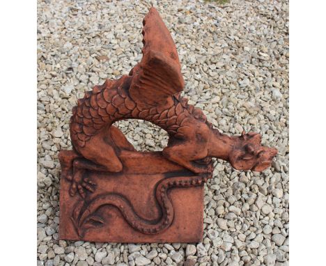 A CAST TERRACOTTA COLOURED SCULPTURE OF A DRAGON with his wings raised on a triangular roof ridge tile, 45cm long
