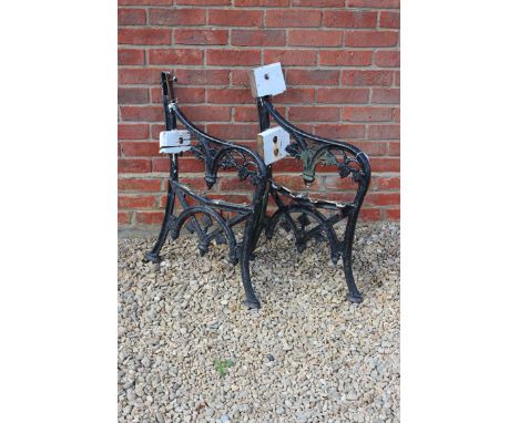 A PAIR OF OLD BLACK PAINTED CAST IRON BENCH ENDS with leaf decoration, 57cm wide