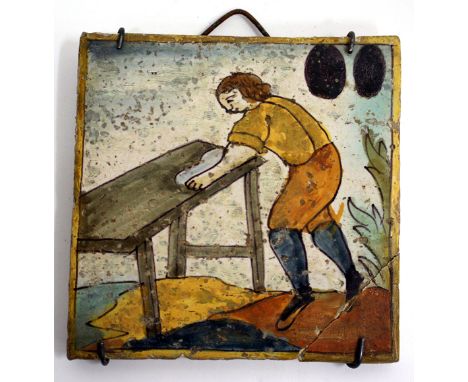 A 17TH CENTURY TIN GLAZED TILE depicting a workman at his bench, 13.4cm square (restorations)