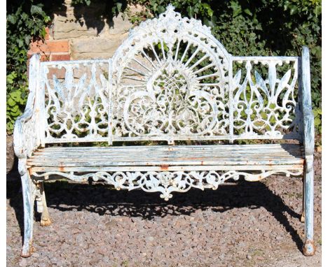 A CAST IRON GARDEN BENCH, the elaborately cast back with raised domed central section with shaped arms and slatted seat, stan