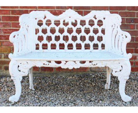 A WHITE PAINTED CAST IRON GARDEN SEAT OR BENCH with pierced scroll decorated backs, sides and seat and standing on cabriole f