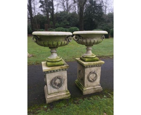 Planter: A pair of composition stone urns on pedestals  late 20th century 123cm high, together with another smaller pair of c