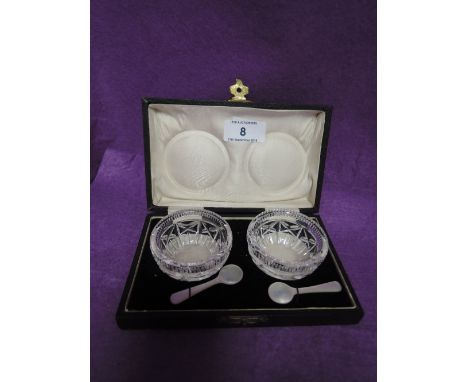 A cased pair of cut glass salts having mother of pearl spoons
