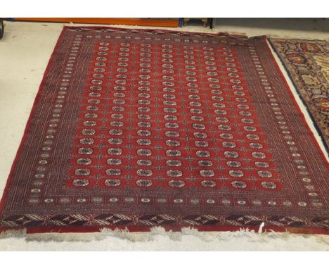 A Bokhara carpet, the repeating elephant foot medallions in cream, salmon, red and blue on a red ground, 253 cm x 323 cm