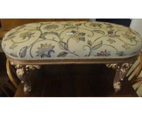 A 19th Century oval giltwood stool raised on acanthus decorated cabriole legs, upholstered in beige scrolling foliate decorat