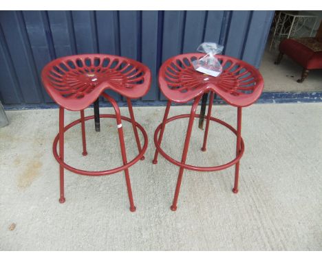 A pair of red painted metal stools in the form of tractor seats*