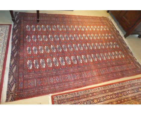 A Bokhara carpet, the repeating elephant foot medallions in cream and mushroom on a terracotta ground, 274 cm x 189 cm