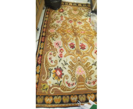 A Kelim carpet decorated with floral motifs in red, orange, yellow, pink and green, on a beige and cinnamon ground, within a 