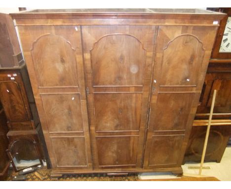 An early 20th Century walnut triple wardrobe compactum in the Dutch taste, raised on ogee bracket feet