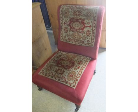 A Victorian salon / nursing chair upholstered with carpet panels in cream and red, raised on turned and ringed front legs to 