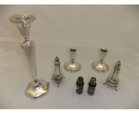 A pair of squat candlesticks on circular stepped base, stamped "Sterling" to base, together with a pair of peppers in the Que