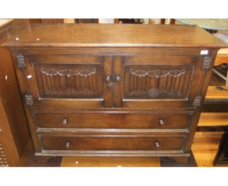 A Goodlys of Leicester oak sideboard with two cupboard doors with linen fold decoration and with two long drawers under, on b