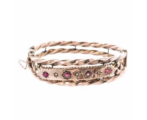 A ROSE GOLD BANGLE of circular hinged form, composed of two twist bands, centred with a plaque embellished with circular mixe