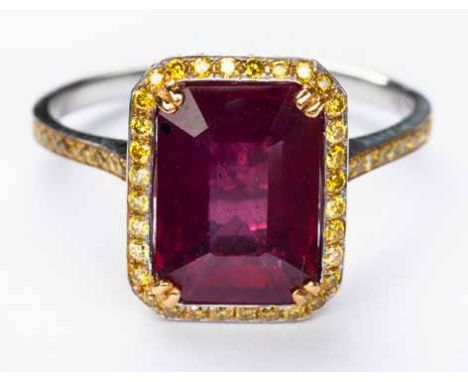 A RUBY AND DIAMOND RING centred with an emerald step-cut ruby weighing 4.14cts, within a surround of round brilliant-cut diam