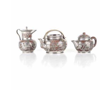A CHINESE YIXING PART TEA SERVICE comprising: a teapot and two creamers, each red-ware bodies with pewter mounts, similarly d
