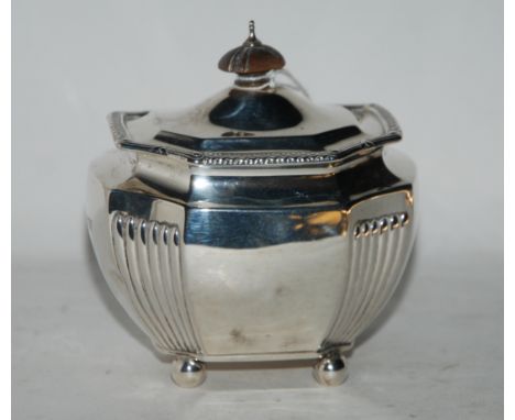 A silver tea caddy, London 1877, of bombe shape with ribbed canted corners on four ball feet with hinged cover 9.5 cm wide 15