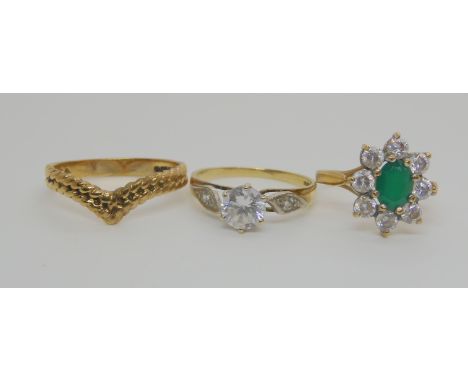 A 9ct gold clear gem set solitaire ring size O, a yellow metal emerald and cz flower ring size K, and a 9ct double twist 'V' 