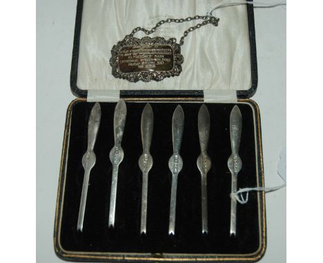 A lot comprising a cased set of six silver shellfish picks, Birmingham 1923 &amp; a silver decanter label inscribed "Presente