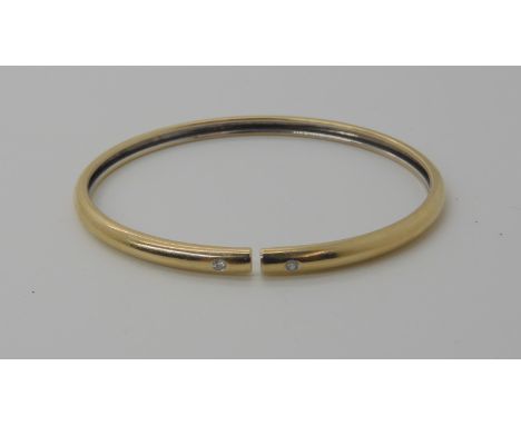 An 18ct gold diamond set bangle, set with two 0.02ct diamonds, approx inner diameter 6cm, weight 10.1gms Condition Report: Th