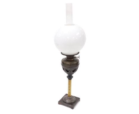 An early 20thC German cast iron and brass oil lamp, the wizard, with chimney and white glass globular shade, 66cm high.