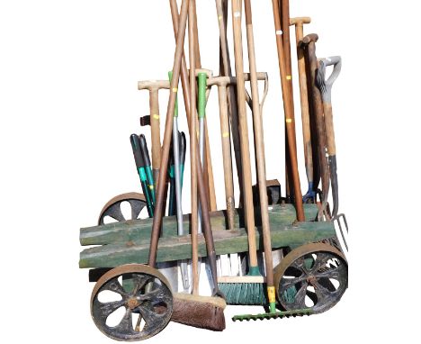 Assorted garden tools, including forks, spades, hoes, shears, and loppers, together with a wooden trolley with cast iron whee