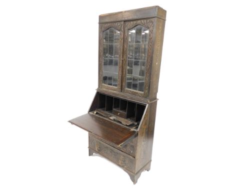 A Victorian oak bureau bookcase, with lion's mask handles, and profusely floral and foliate carved, the plain pediment over a