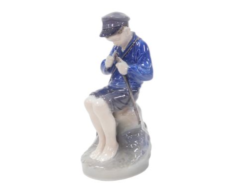 A Royal Copenhagen porcelain figure of a boy, modelled seated whittling a stick, number 905, printed and painted marks.