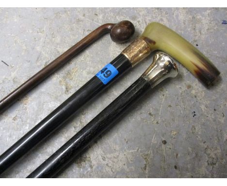 A silver topped ebony cane with gold banding, a horn handled walking cane and a rustic stick