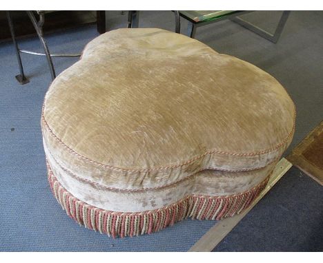 A large overstuffed pouffe in a clover leaf design with tasselled trim