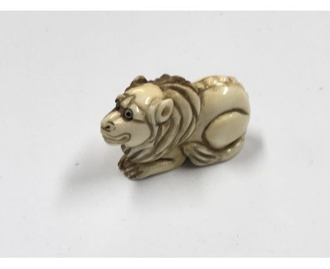 A Japanese carved Ivory Netsuke of the Meiji period in the form of a lion. Signed base.