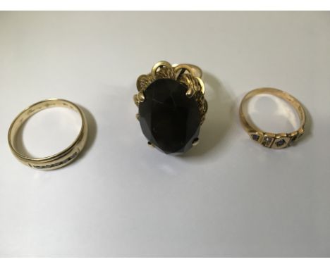 Three quality gold rings, a 14ct elaborate gold and smokey quartz cocktail ring, size K, a 9ct diamond band ring size S and a