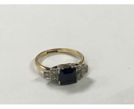 A blue sapphire and diamond ring of Art Deco design with a square cut central stone flanked by diamonds.