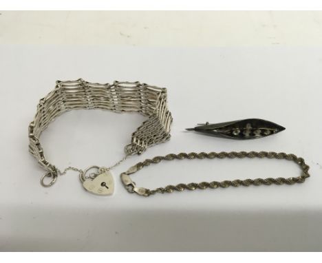 A silver gate bracelet, silver brooch and silver bracelet.