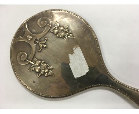 A silver backed hand mirror with assay office marks for Chester, the back decorated with foliage.